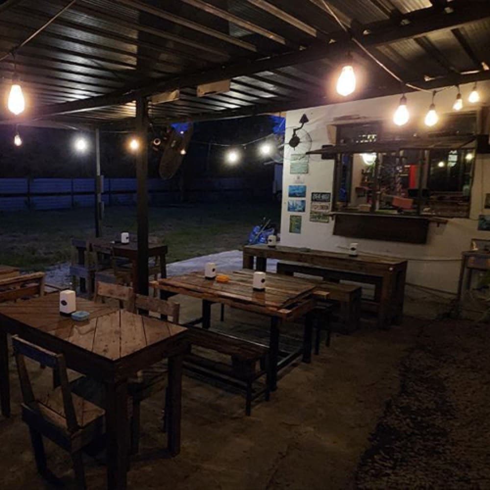 The covered patio at night, with string lights and long benches