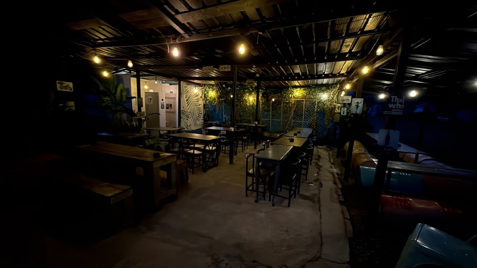 The covered seating area at night, string lights along a tin roof